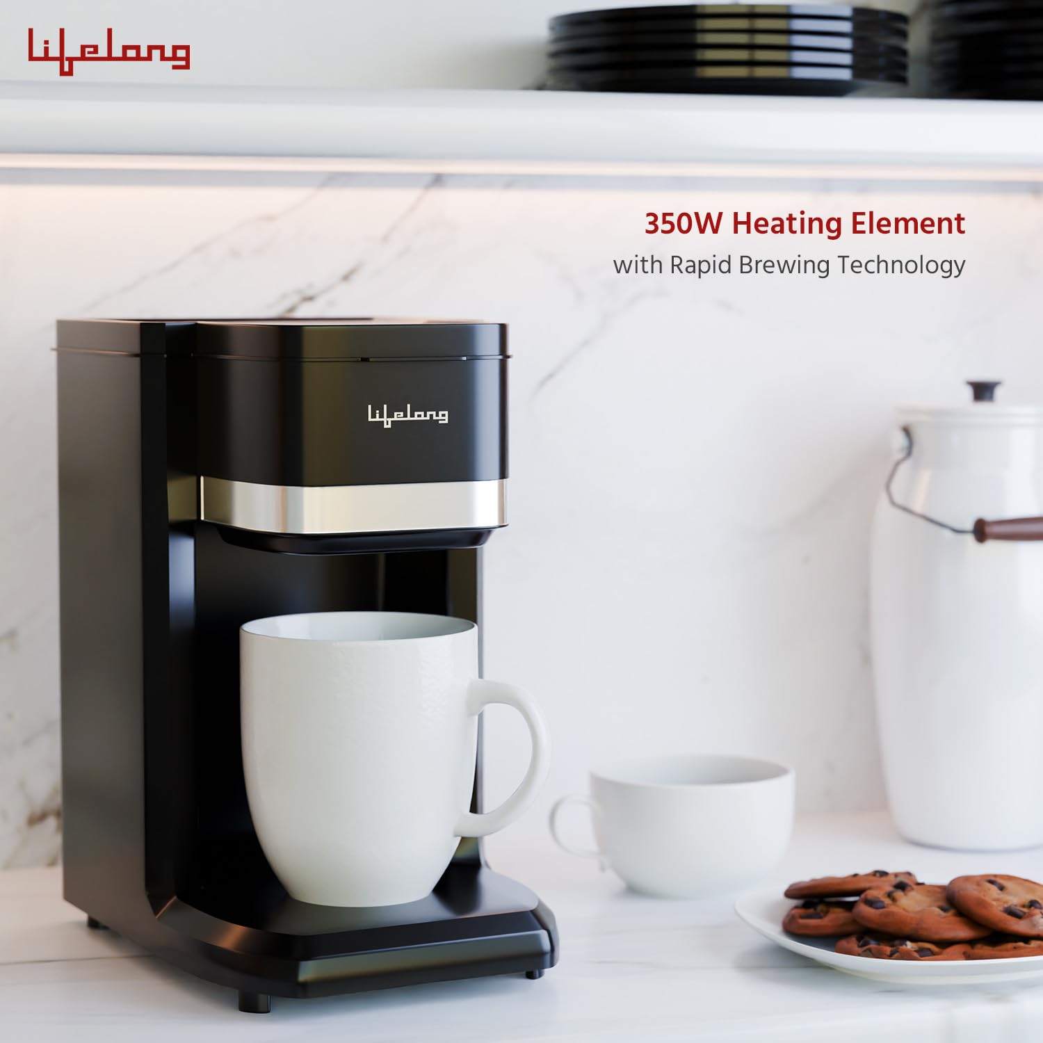 A black Lifelong coffee maker with a silver accent band sits on a white marble countertop with a white mug placed underneath. A second mug, a plate of cookies, and a white canister are visible in the background.
