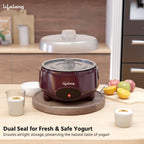 Yogurt maker on a kitchen counter with fruits and glasses of yogurt.