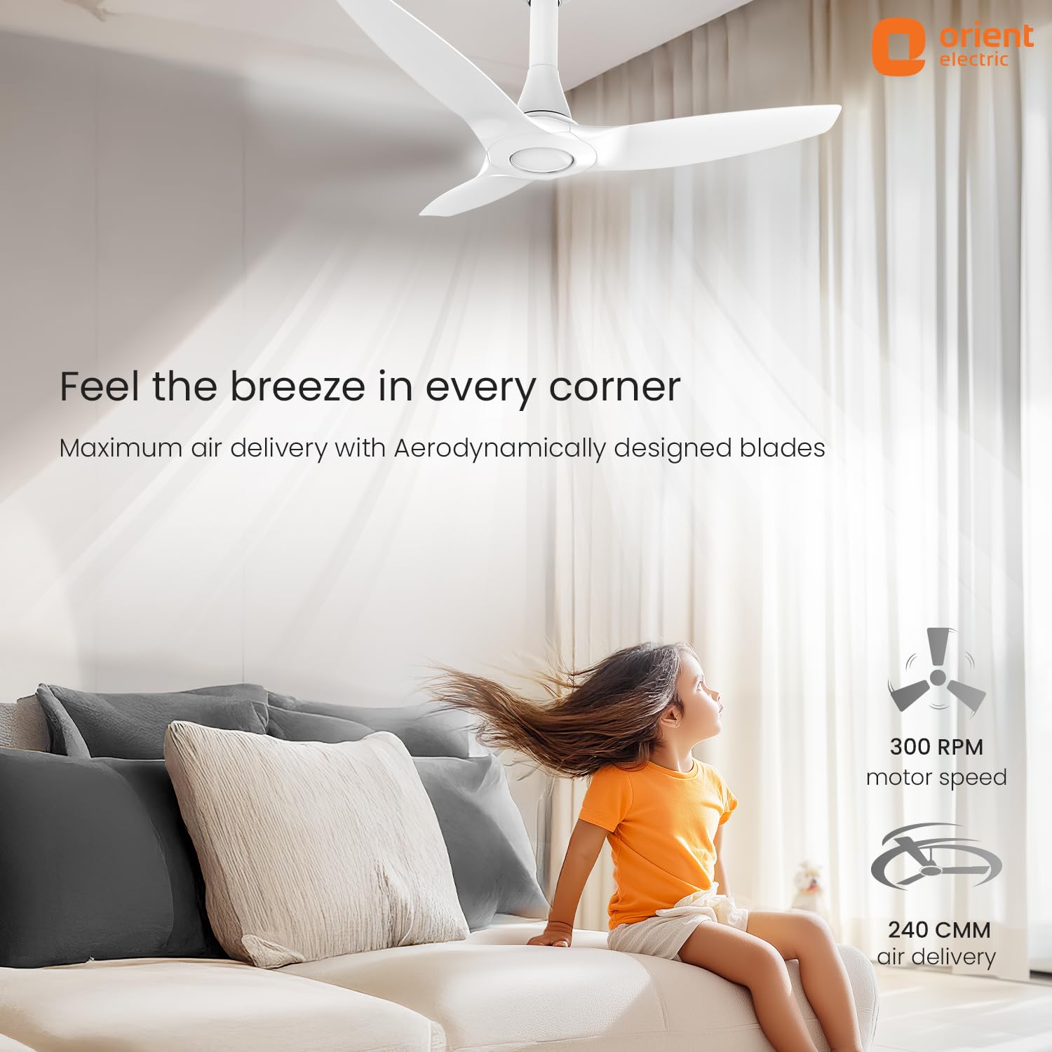 Living room with a ceiling fan and child enjoying the breeze, Orient Electric branding visible.