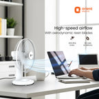 Orient Electric fan on a desk with a laptop and person using it, in an office setting.
