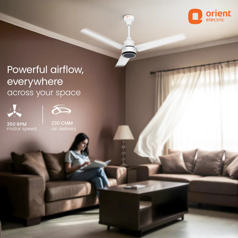 Living room with a person on a couch using a tablet, ceiling fan, and 'Orient Electric' branding.