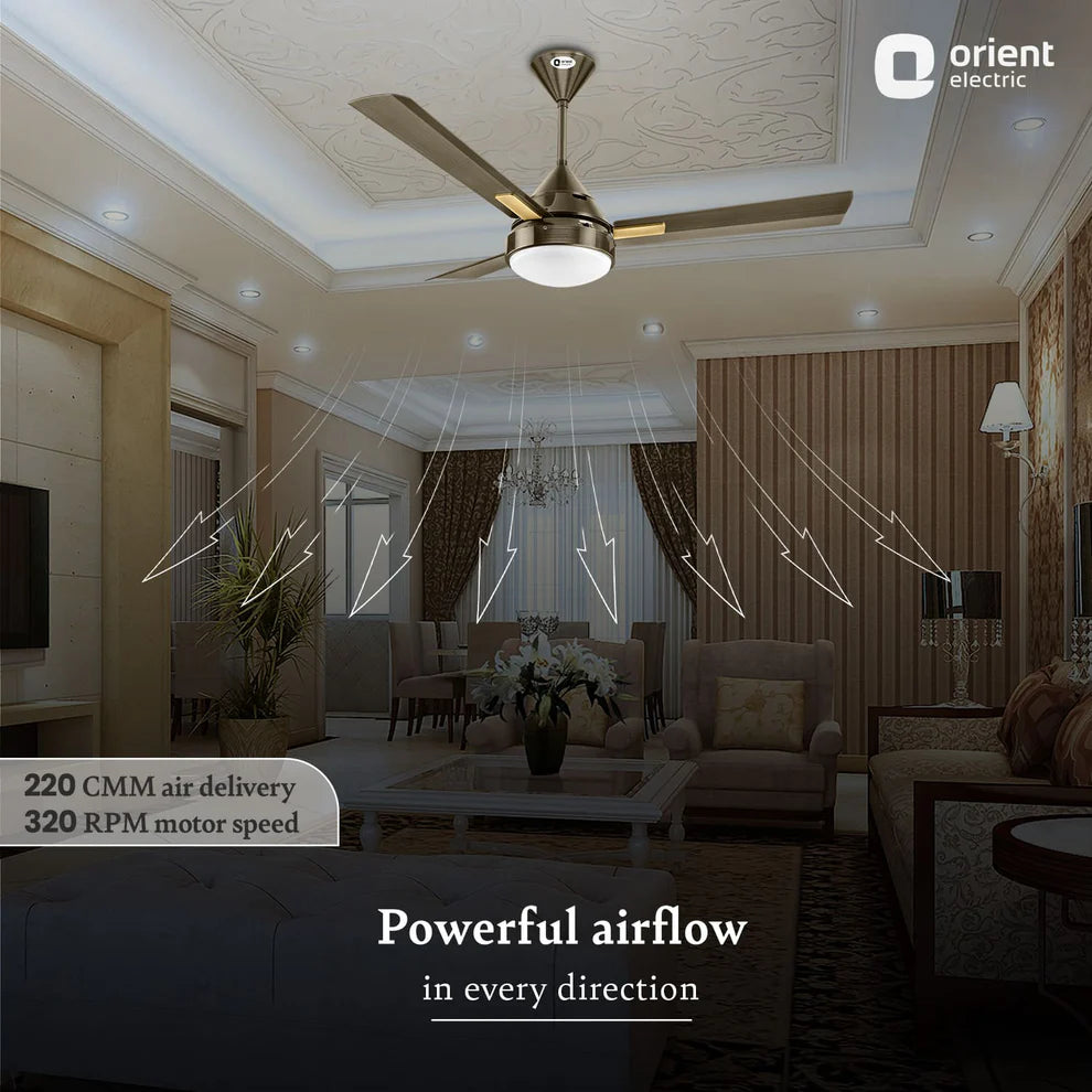 A modern ceiling fan with a brushed metal finish and three wooden blades, shown installed in a decorated living room. White graphic lines illustrate airflow patterns radiating from the fan, with text overlays highlighting '220 CMM air delivery' and '320 RPM motor speed'.