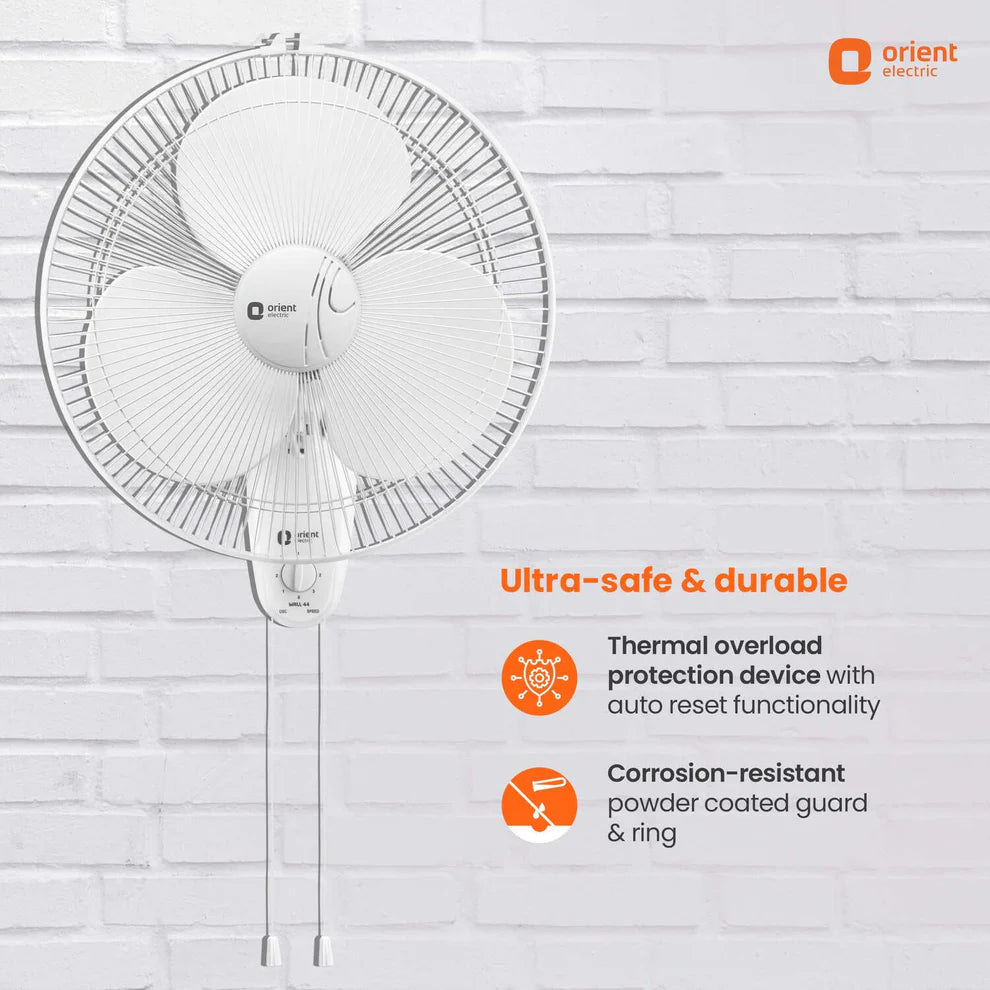White Orient Electric wall fan with a circular wire guard and hanging cord, shown against a white brick wall with orange text highlighting durability and protection features.